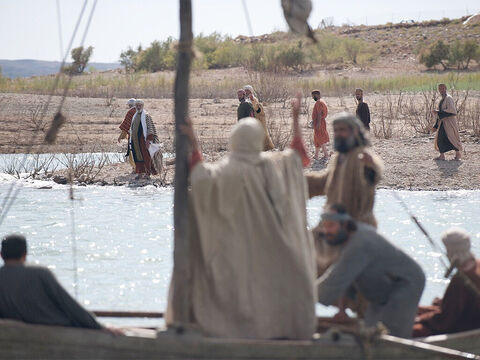 Uma grande multidão, muitos deles peregrinos a caminho da festa da Páscoa em Jerusalém, observavam o barco e o seguiam a pé pela costa para encontrar Jesus. – Slide número 2