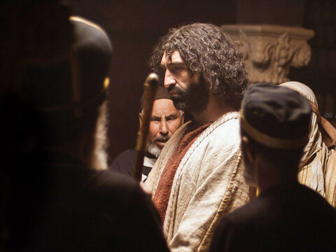 Após ter sido interrogado por Anás, Jesus foi levado perante Caifás, o sumo sacerdote, e os líderes judeus (Sinédrio) que haviam sido reunidos naquela noite. – Slide número 1